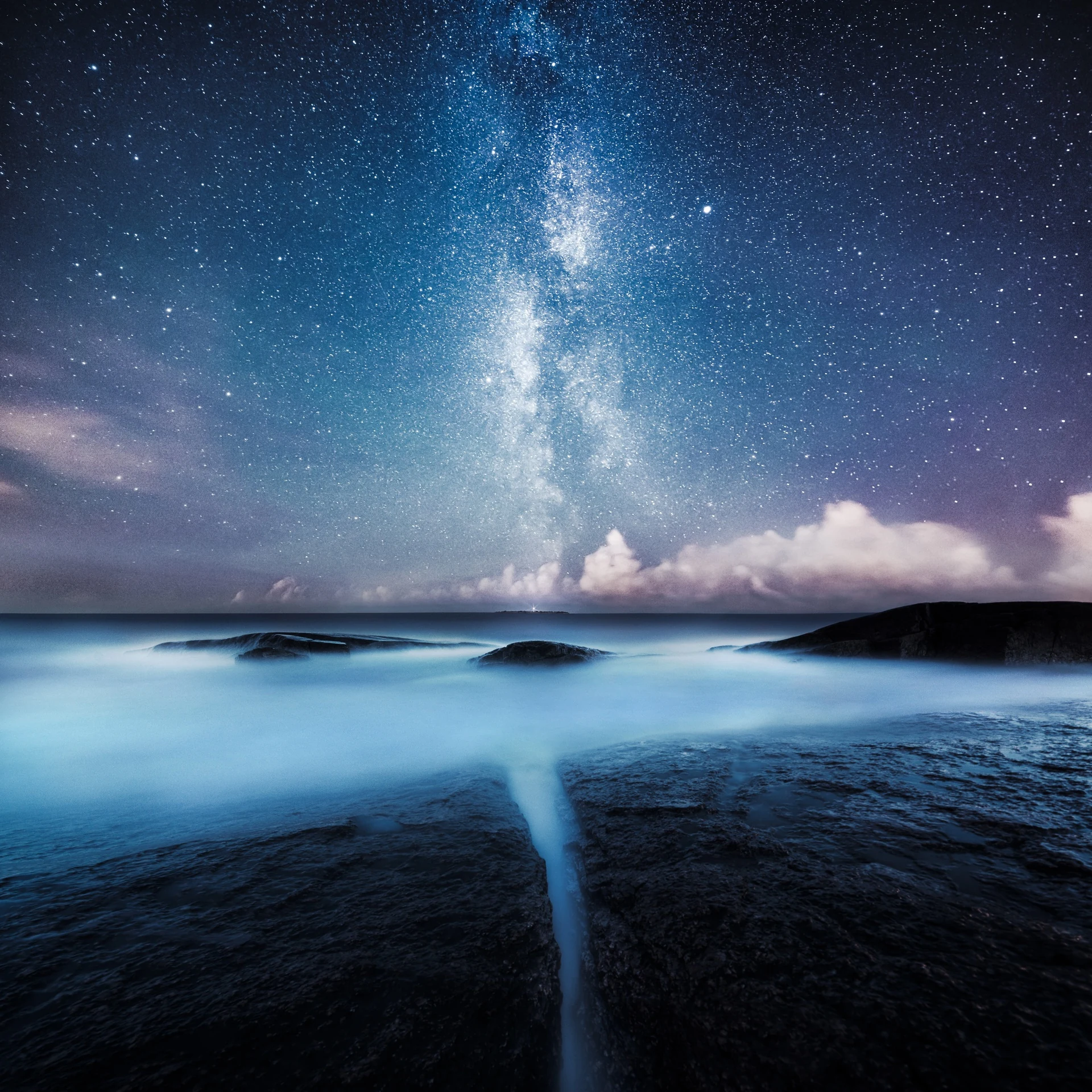 Narrow opening between dark water and land beneath the Milky Way